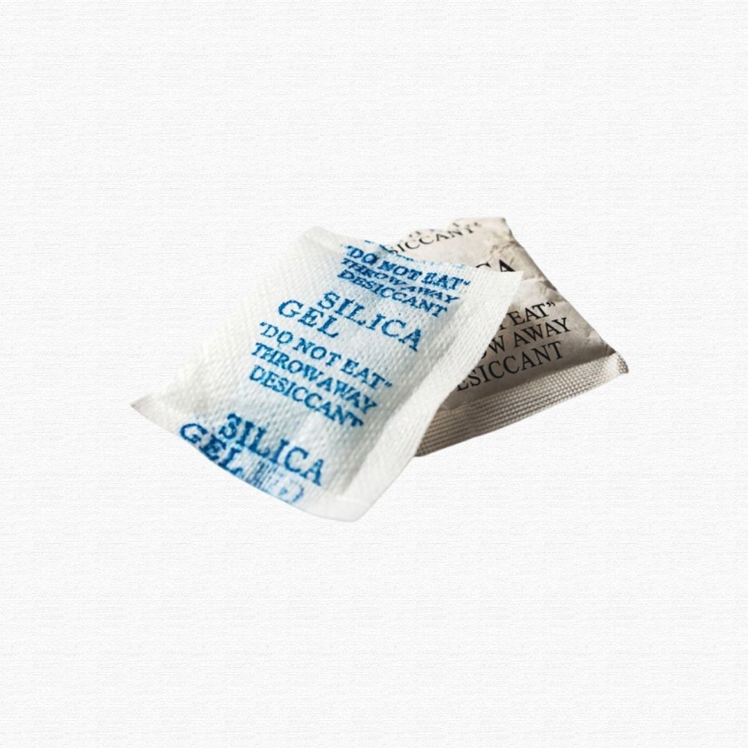 Small paper packets of clear silica gel beads.